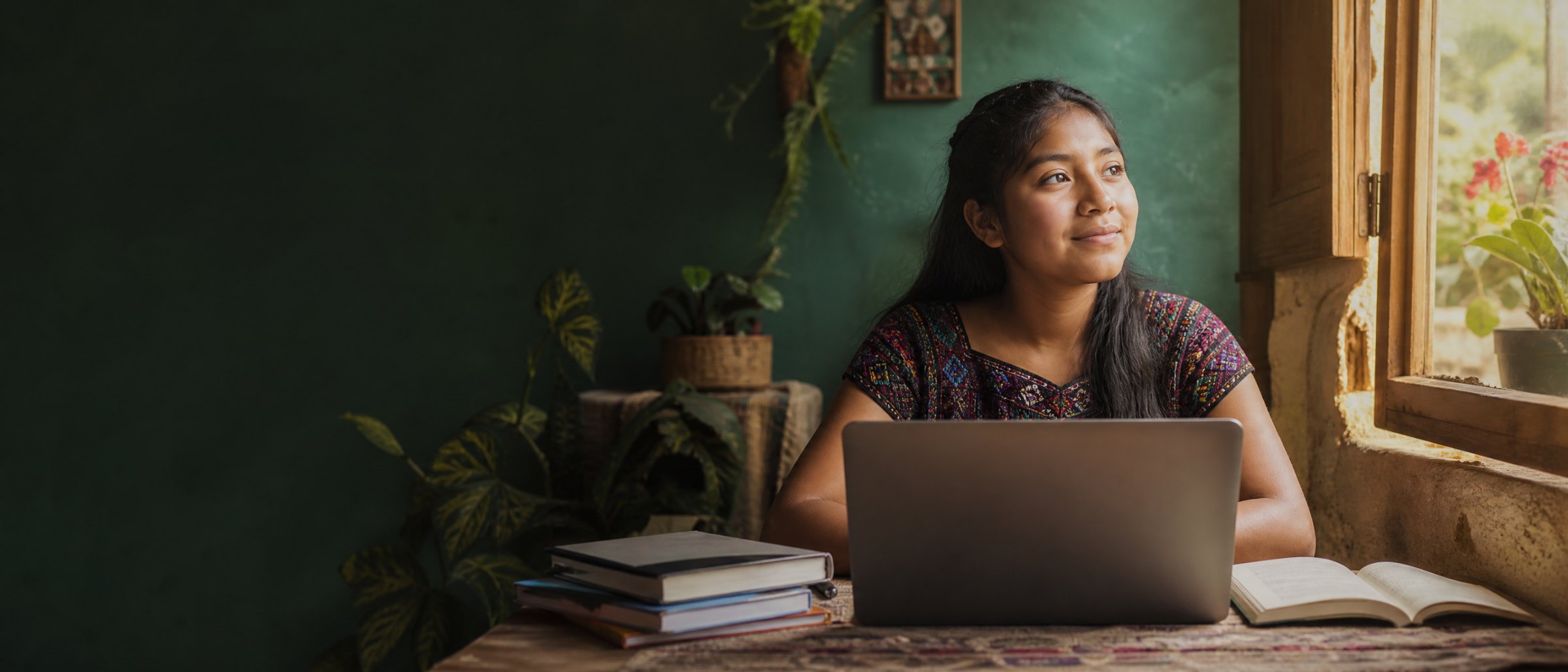 A student using a laptop beside a window